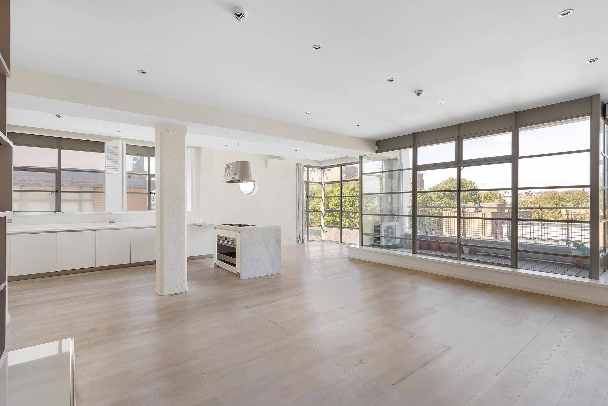 Corner loft flat, 1,321 sq ft of lateral living with high ceilings, large windows, balcony with canal views. Open-plan kitchen, laundry room, 2 bathrooms, AC, underfloor heating, parking, 24-hour porter, gated development. 10-min walk to Angel.