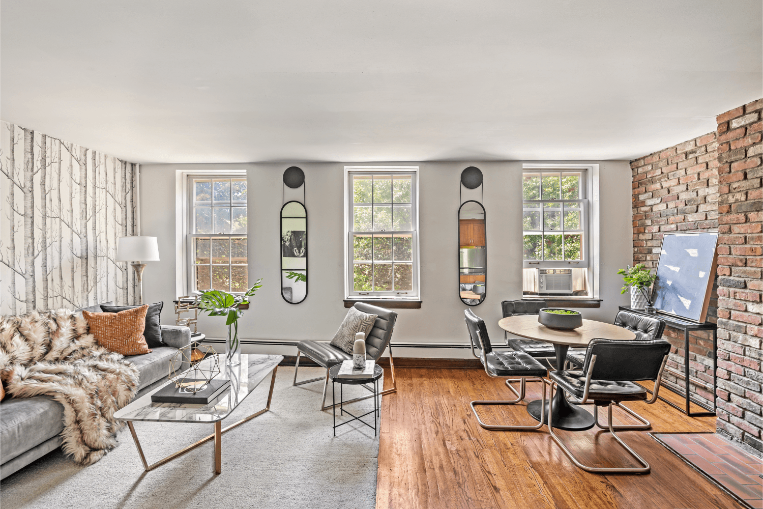 The tastefully done kitchen opens up to a spacious living and dining area, adorned with exposed brick, stylish wallpaper and hardwood floors.