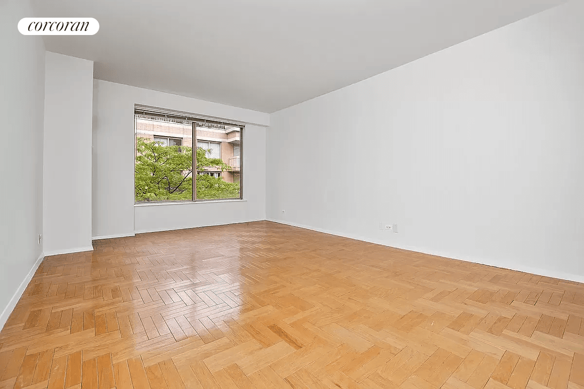 Spacious, tranquil, and well lit studio apartment with high ceilings and large windows offering serene views of the building's garden courtyard.