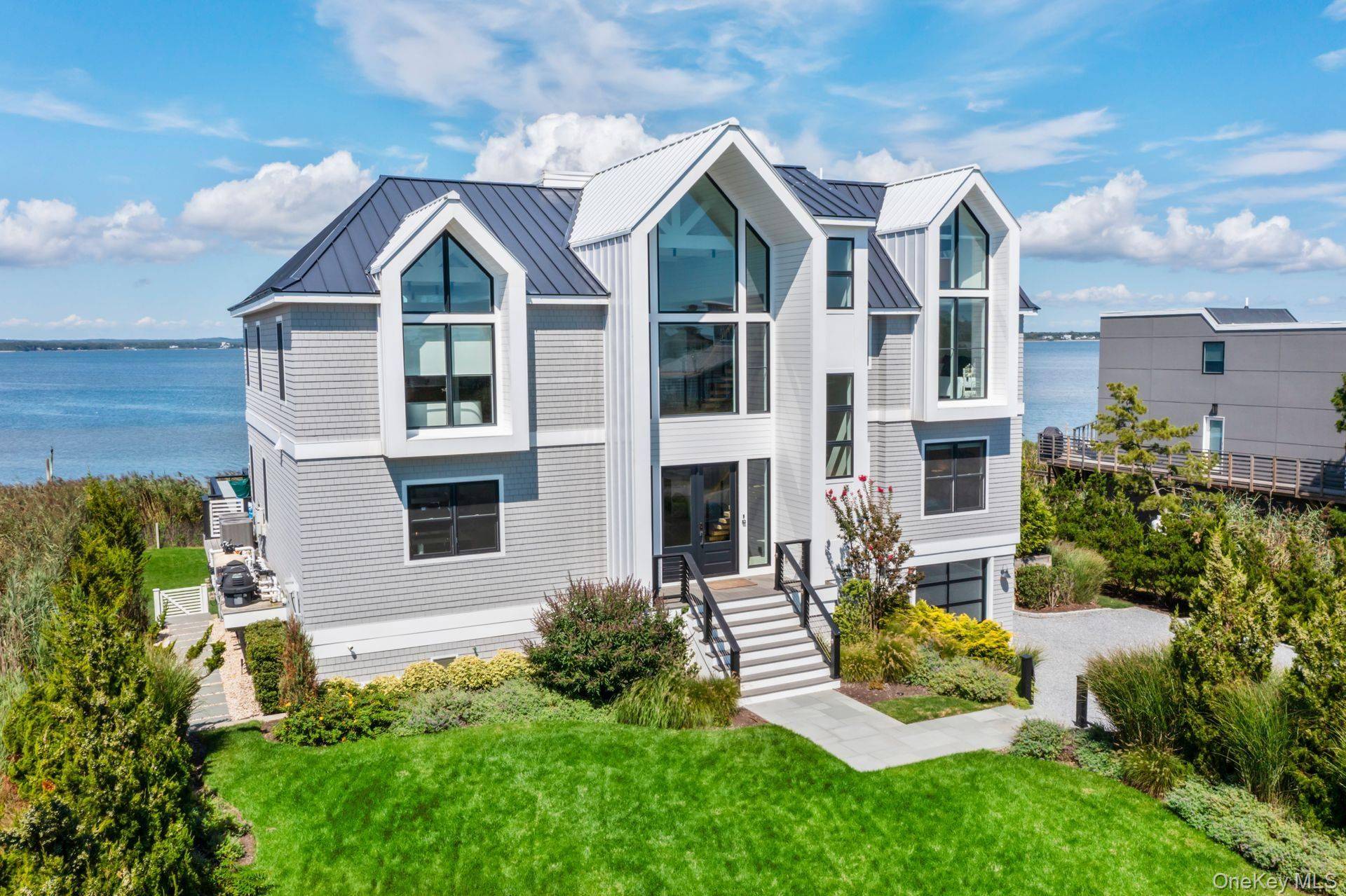 Discover Coastal Elegance at its Finest in Westhampton Dunes Sitting gracefully on 105 feet of open bayfront, this stunning residence epitomizes the pinnacle of modern luxury and design.