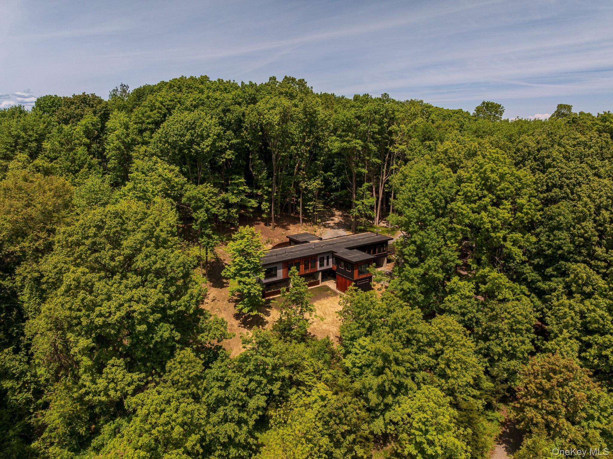 THE GREAT ESCAPE Nestled on 10 ultra private acres with breathtaking views of the Taghkanic Hills, this thoughtfully designed home blends modern architecture with warmth, natural materials, and exceptional craftsmanship.