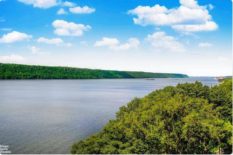 NOTHING SHORT OF PHENOMENAL A wall of windows spanning the living and dining room magnificently frames the unobstructed views of the Hudson River, the Palisades and beyond.