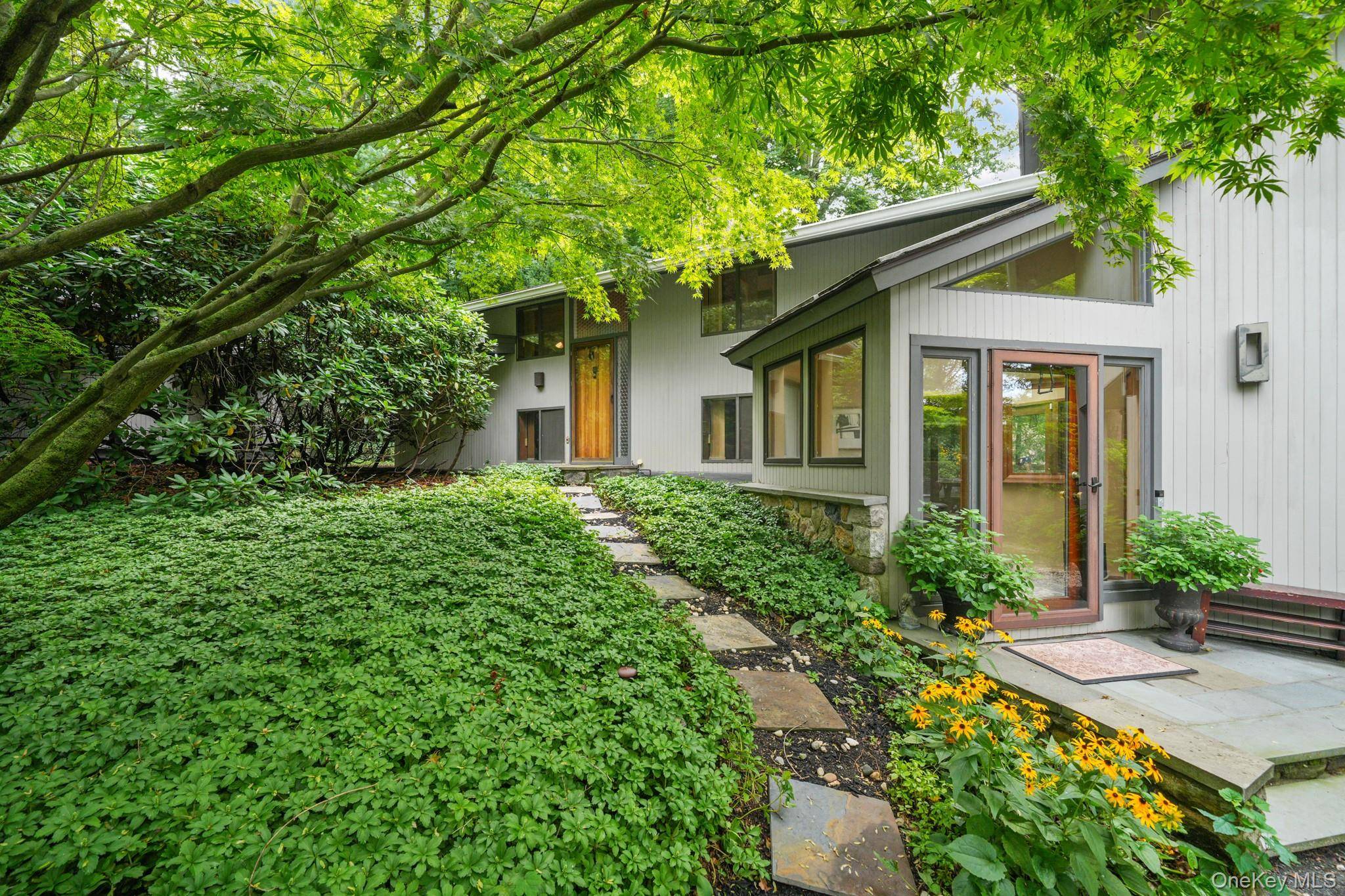 Mid Century Modern elegance meets cottage core charm in this architecturally distinctive cedar home, tucked away in a serene enclave just off the Hudson River.