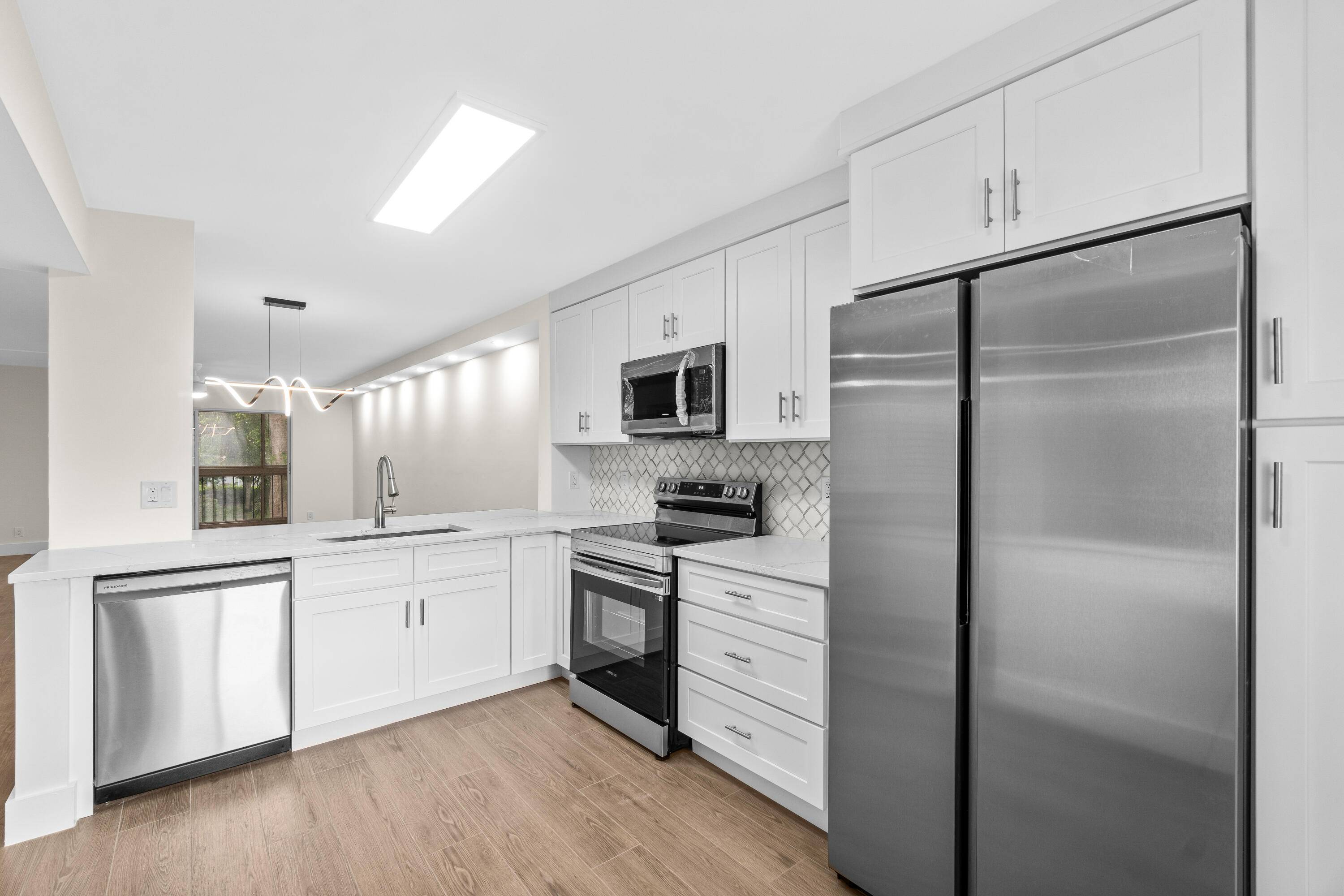 Waterfront remodeled unit featuring wood look tiles white shaker cabinets designer quartz countertop marble backsplash new stainless steel appliances and washer and dryer and much more.