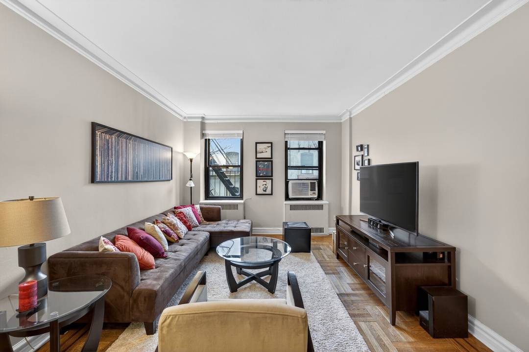 Gracious and spacious pre war corner one bedroom featuring classic Art Deco architectural details, including a step down living room, elegant arched entryways, hardwood floors, and soaring high ceilings.