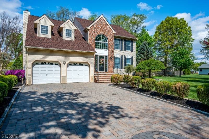 Distinguished brick front Colonial with vinyl siding, beautifully set on a professionally landscaped property with custom paver driveway, underground sprinklers, and exceptional resort style outdoor living.