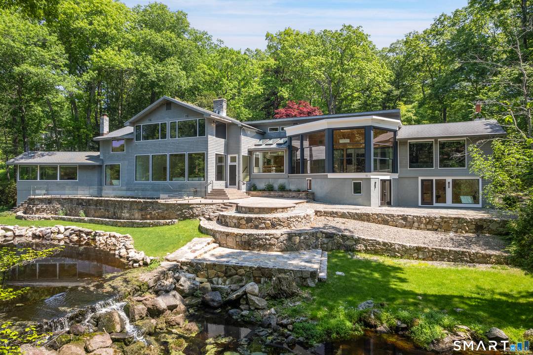 Extraordinary riverfront modern retreat set against a breathtaking backdrop of waterfall, woodland, and sweeping water views in one of Weston's most remarkable settings.