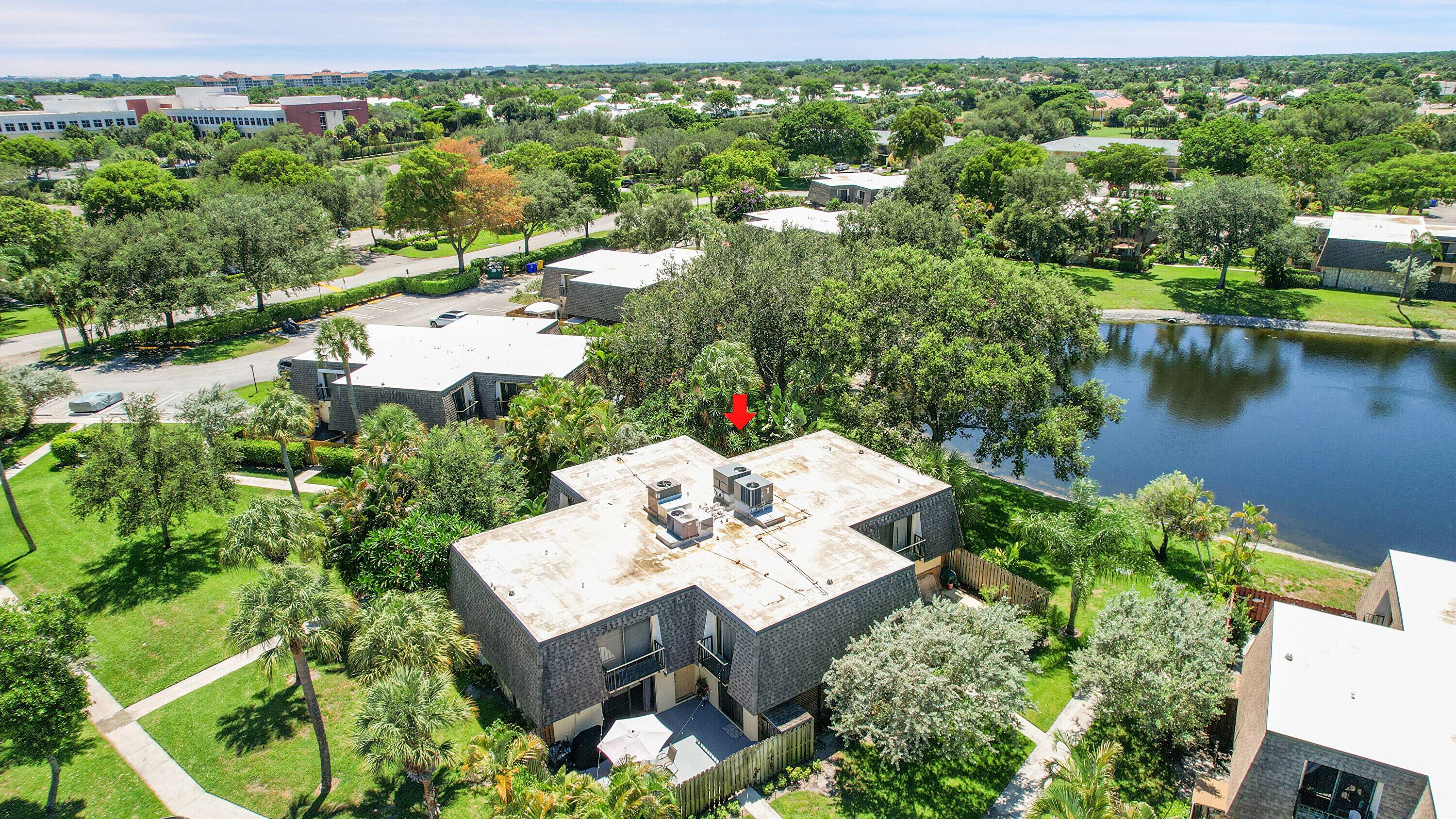 Serene 2 bedroom, 2 bath corner, courtyard townhome offering shimmering lake views from a secluded patio with privacy fence, framed by lush, verdant landscaping that invites peace and relaxation.