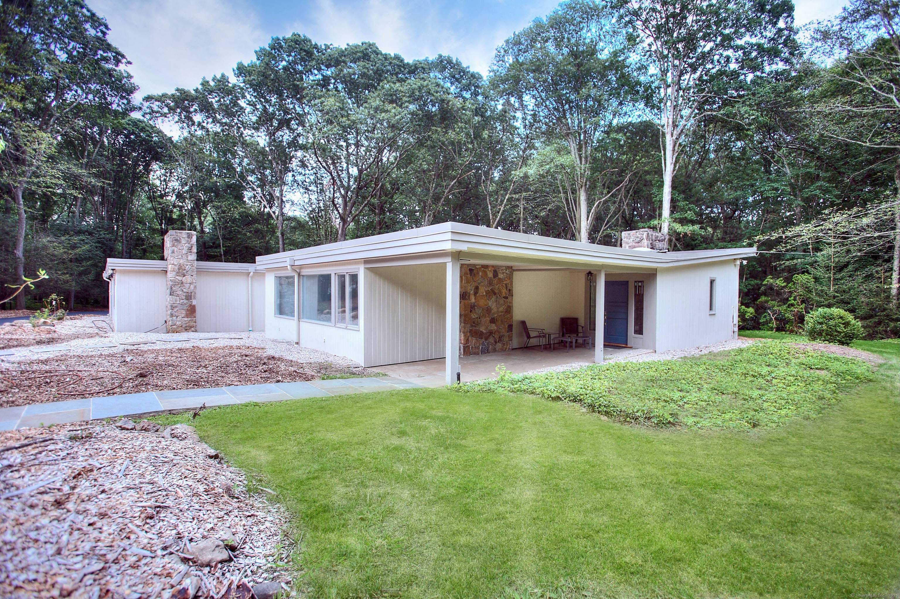Discover the charm of this mid century modern home, bathed in natural sunlight thanks to large windows that frame stunning views of the lush landscaping and nature outside.