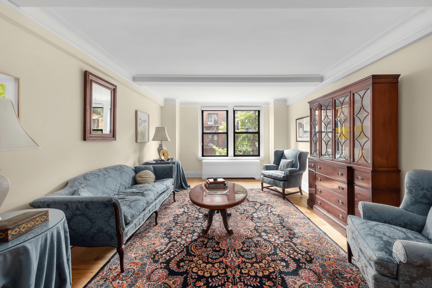 Step into the classic combination apartment through a gracious foyer, leading into an oversized living room with a beamed ceiling and hardwood floors, facing south.