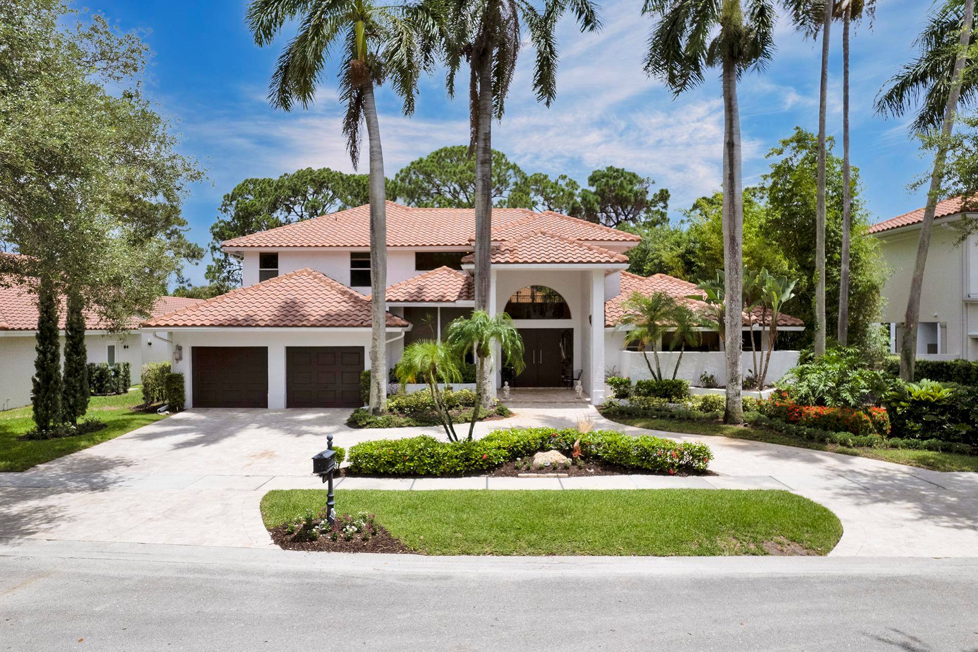 A marble driveway lined with palm trees leads you to the entrance.