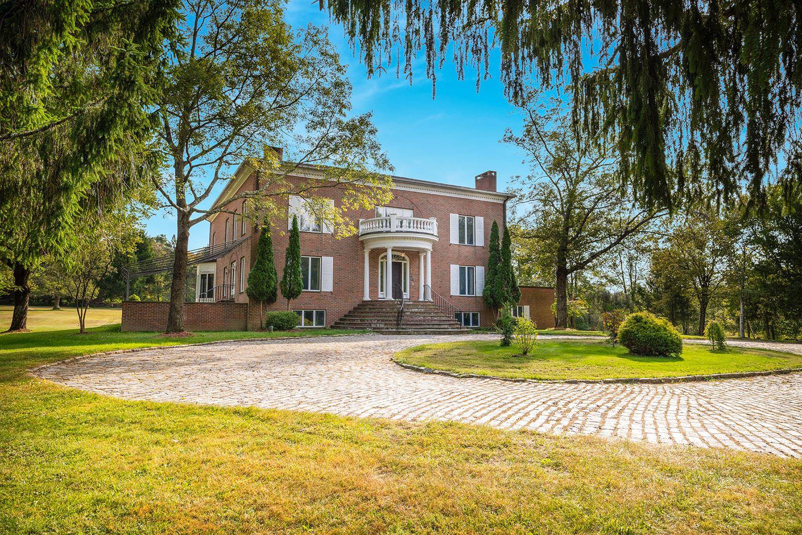 Exceptional living awaits in this stately Georgian manor house sitting on 7 acres at the top of prestigious North Quaker Hill Road.