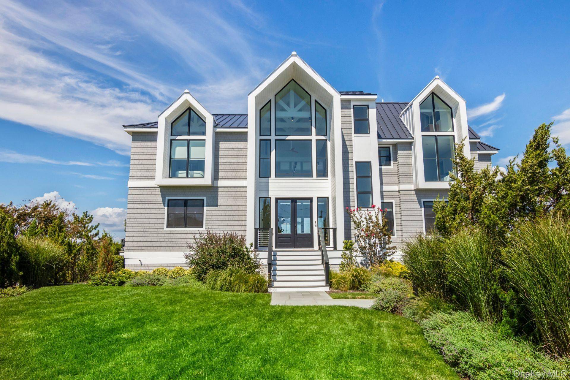 Discover Coastal Elegance at its Finest in Westhampton Dunes Sitting gracefully on 105 feet of open bayfront, this stunning residence epitomizes the pinnacle of modern luxury and design.