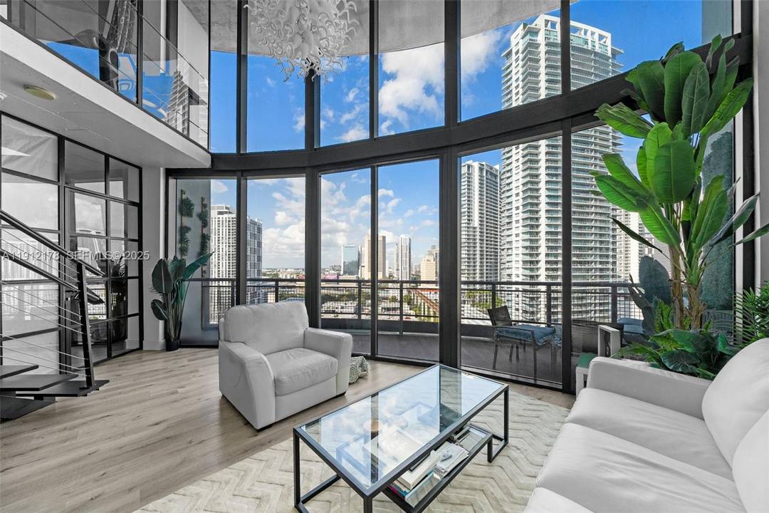 Stunning two story industrial loft in the heart of Brickell featuring dramatic double height ceilings, expansive glass walls, and unobstructed skyline and river views that transform every room into a ...