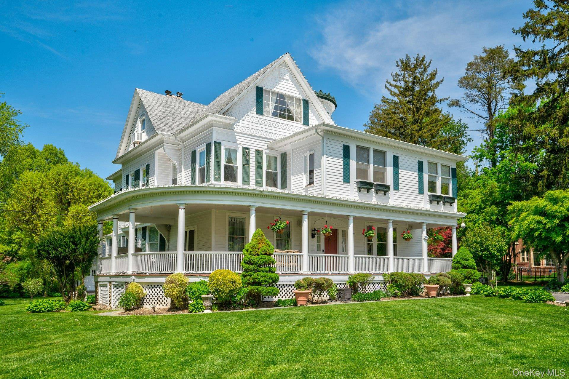 Estate gates mark the entrance to a meandering drive surrounded by flowering gardens and specimen trees leading to the elegant turn of the century Victorian home.