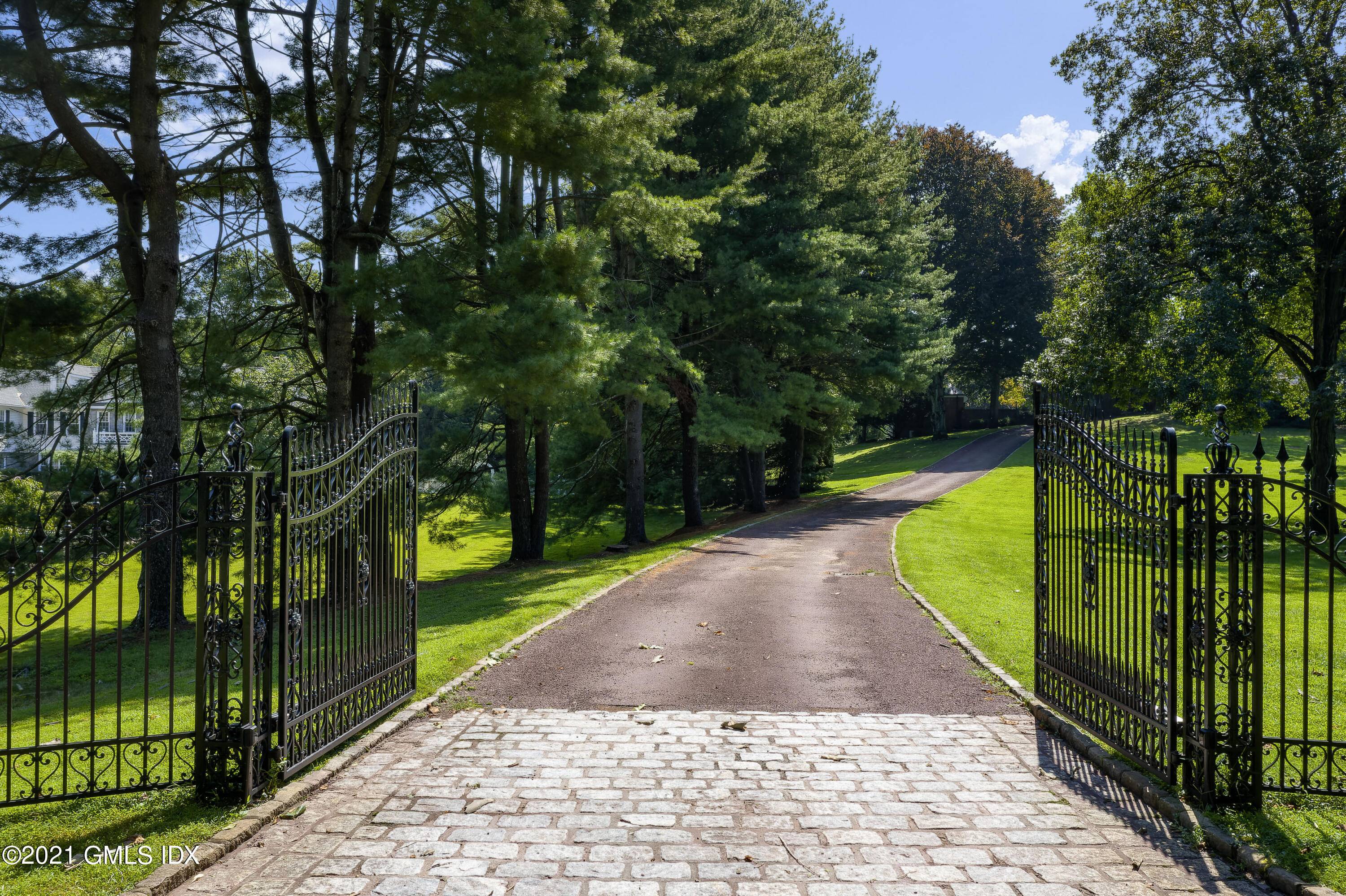A long gated drive approaches the brick stone English Manor originally built for a 1930's heiress.