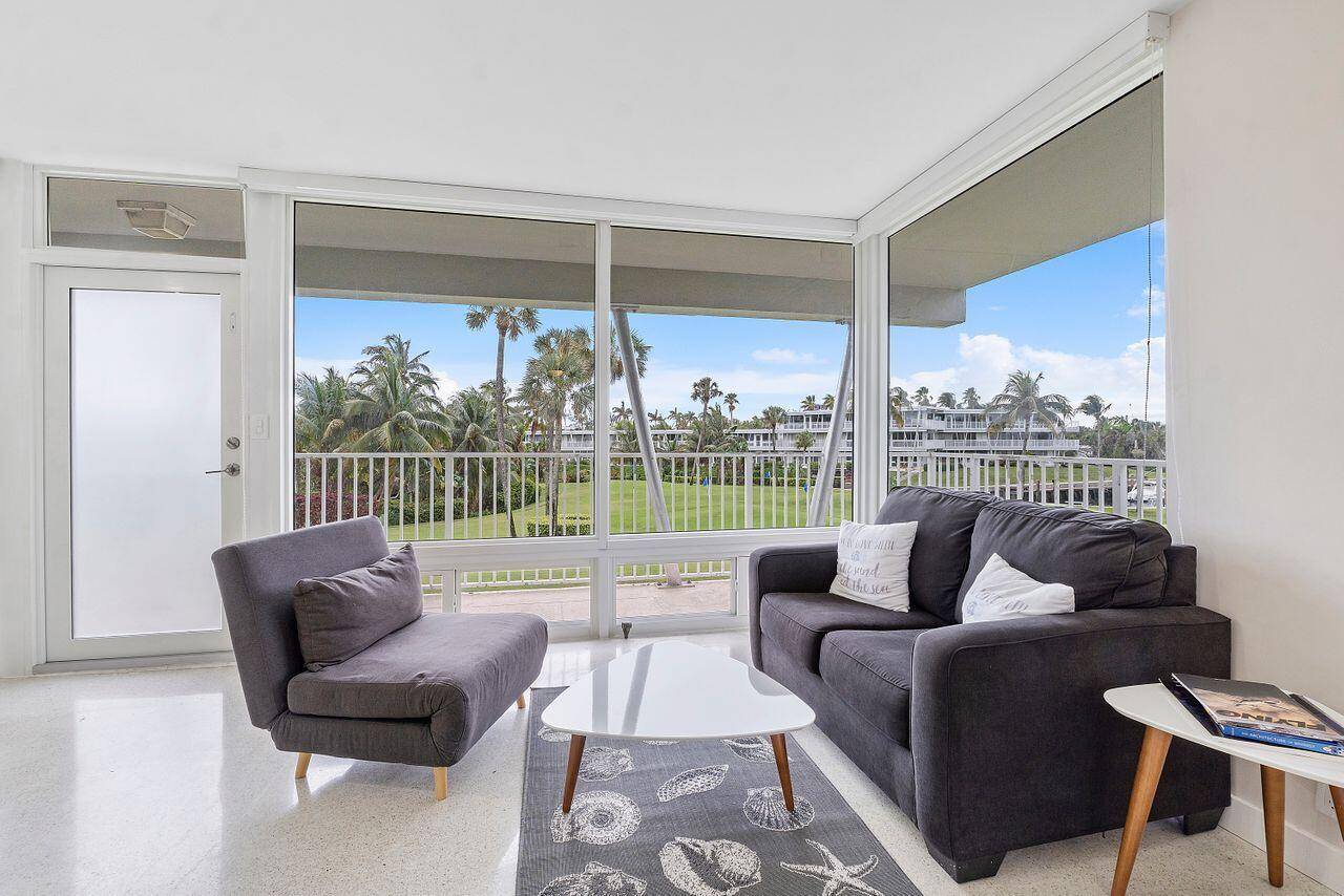 Beautifully renovated mid century modern corner unit with floor to ceiling impact glass, seamlessly blending indoor and outdoor living while showcasing expansive views of the golf course, marina, and intracoastal.