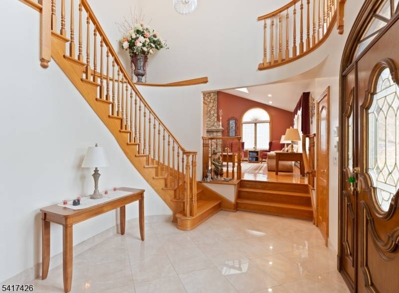 Welcome to this impressive custom brick and stone Colonial, offering exceptional curb appeal with a beautifully paved driveway and grand front staircase leading to the elevated main entrance.