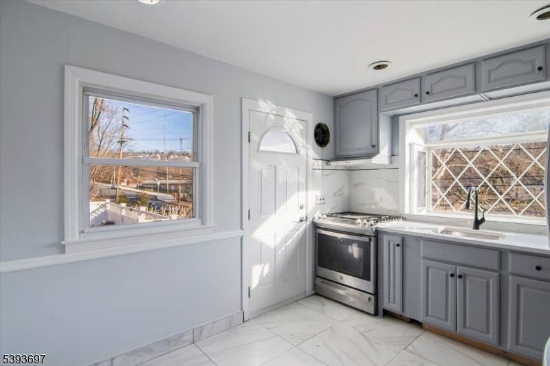 A paver walkway leads to a welcoming open front porch at this renovated raised ranch, set on a desirable corner property.