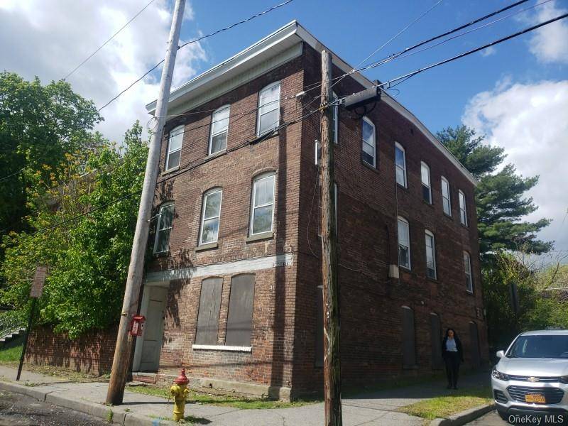 Large three family brick building on corner lot with fenced in yard.