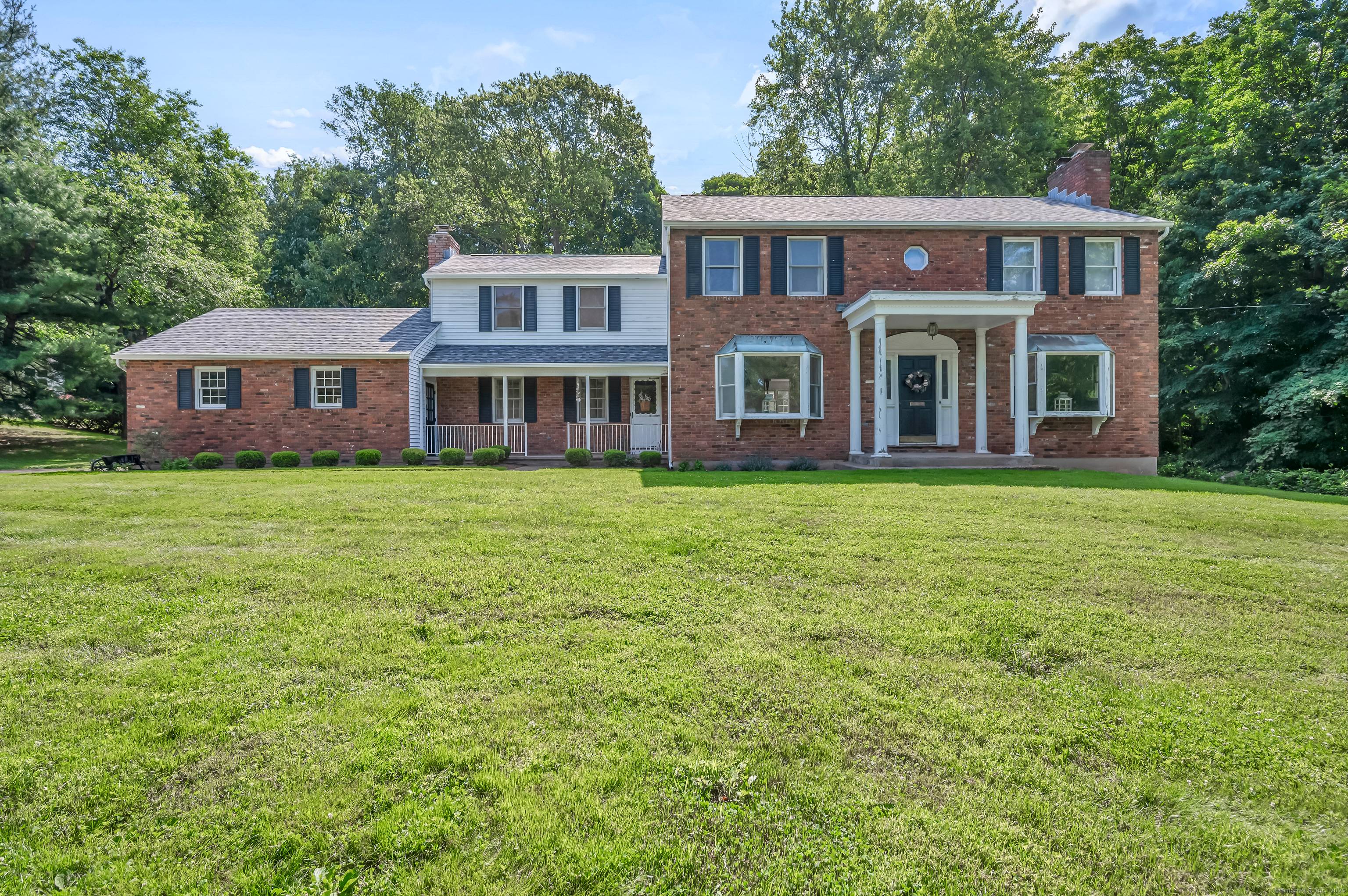 This classic colonial home features timeless charm with a stately brick front and elegant white pillar entryway.