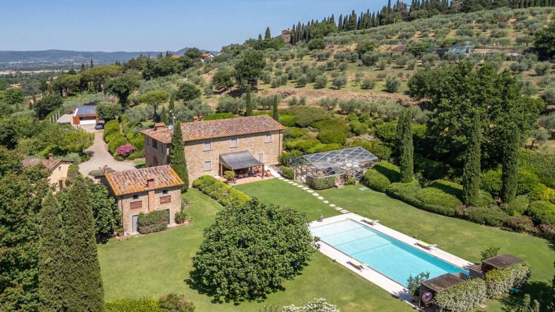 Exclusive panoramic villa with swimming pool, outbuildings and 12.9 ha of olive groves and arable land for sale a few km from Arezzo, Tuscany.