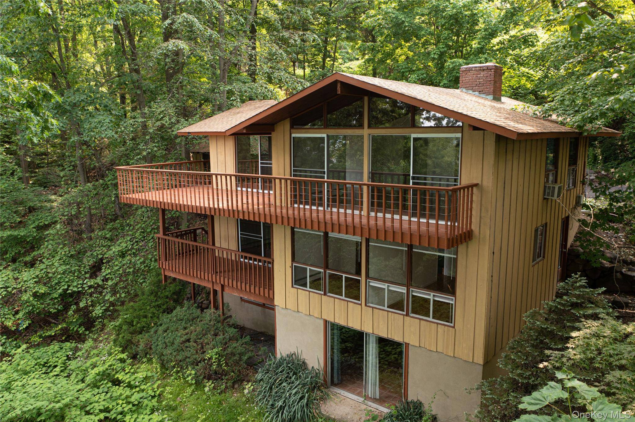 Iconic Mid Century Modern tri level Techbuilt home, constructed in redwood and glass, and privately tucked away on a sloping wooded acre with direct access to the Old Erie Rail ...
