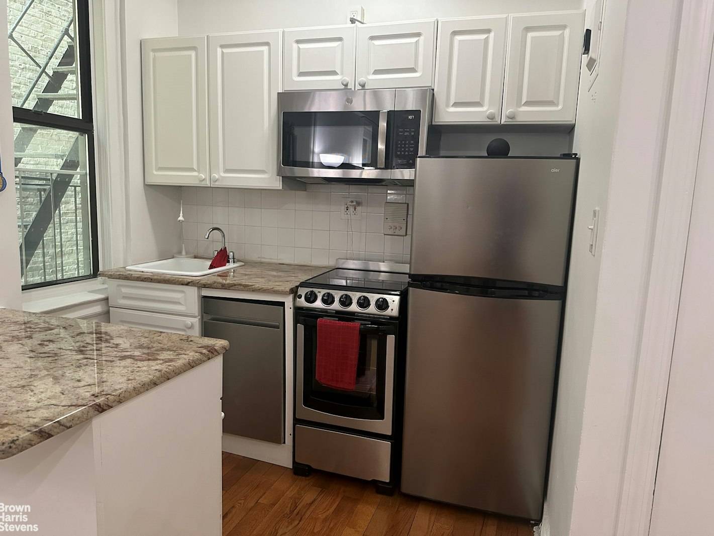 This cozy abode boasts a newly renovated kitchen with sleek stainless steel appliances, white cabinetry, and granite countertops.
