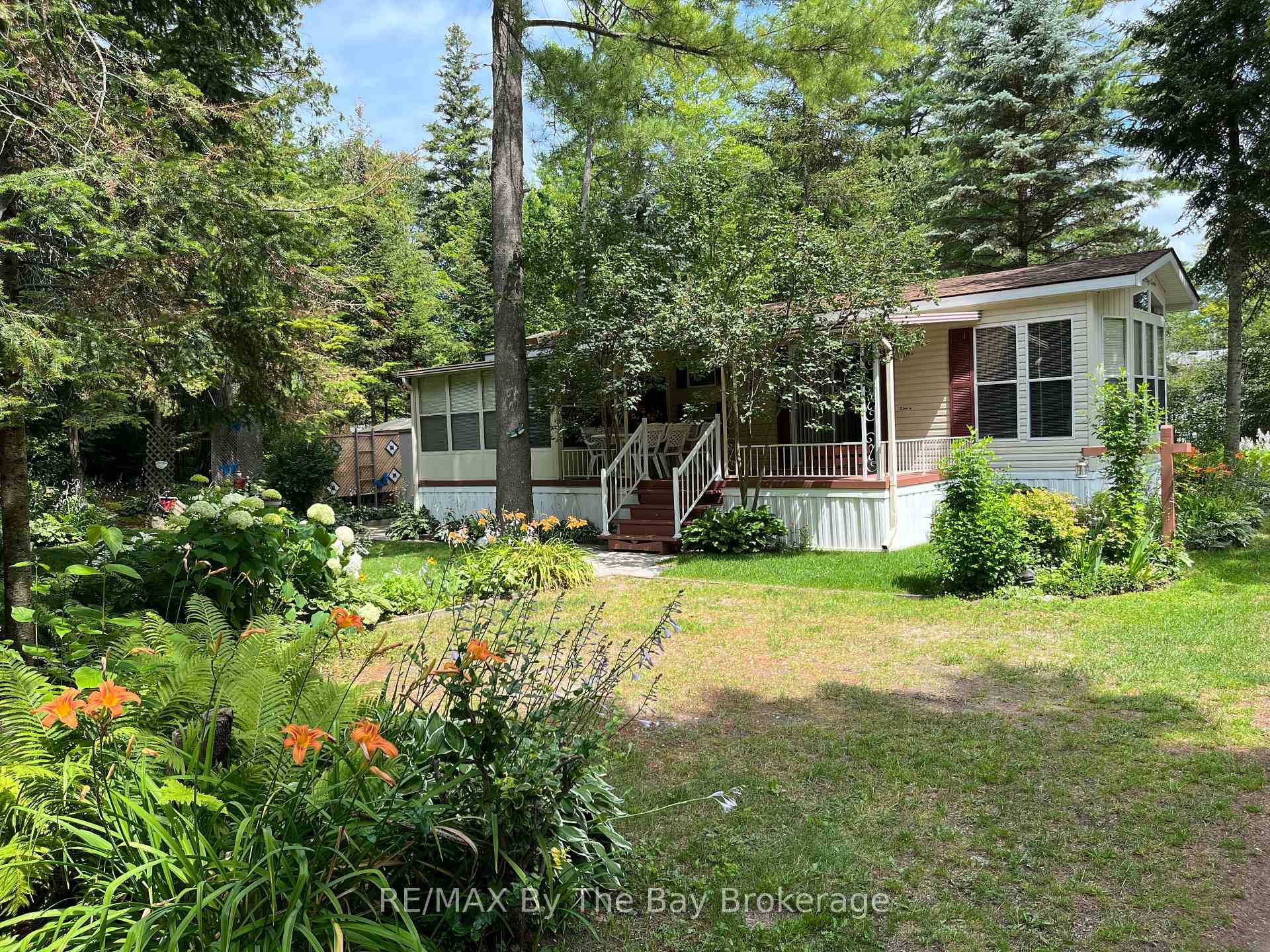 This charming, 3 bedroom seasonal cottage is nestled in lush greenery within the beautiful Wasaga Country Life Resort, offering a serene retreat with a lovely porch and vibrant garden.