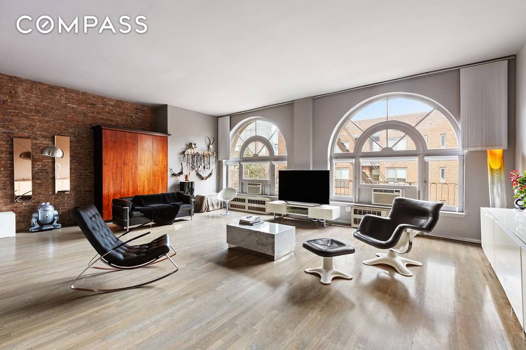 This chic and stylish, sunny Chelsea loft has 12 foot ceilings with two rare, expansive floor to ceiling arched windows, classic details like a cast iron column and exposed brick, ...