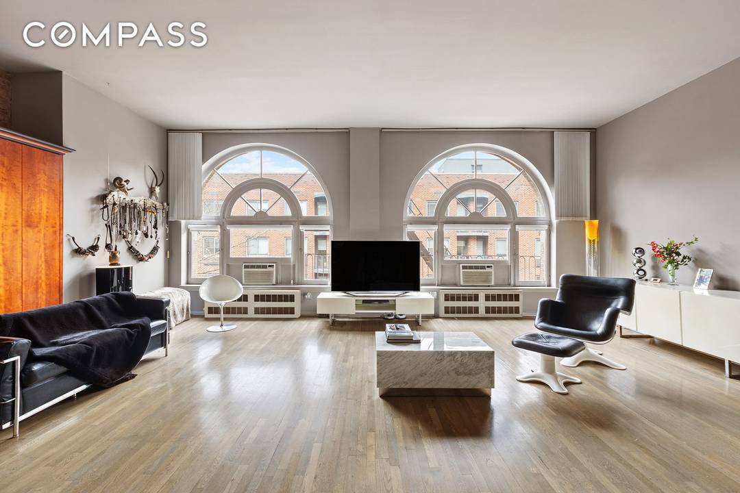 This chic and stylish, sunny Chelsea loft has 12 foot ceilings with two rare, expansive floor to ceiling arched windows, classic details like a cast iron column and exposed brick, ...
