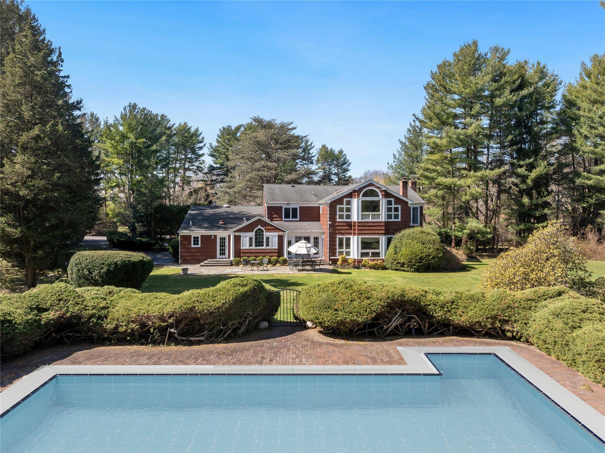 Welcome to this stately columned brick and shingle Colonial, nestled amidst lush landscaping that perfectly complements its timeless architectural elegance within the esteemed Village of Old Brookville.