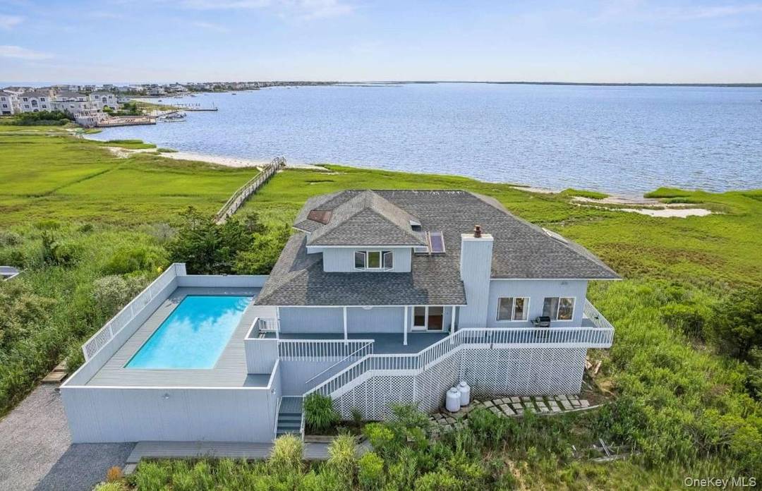 Perched along Dune Road, this delightful two story home captures stunning sunrises and sunsets with sweeping bay views visible from nearly every room.