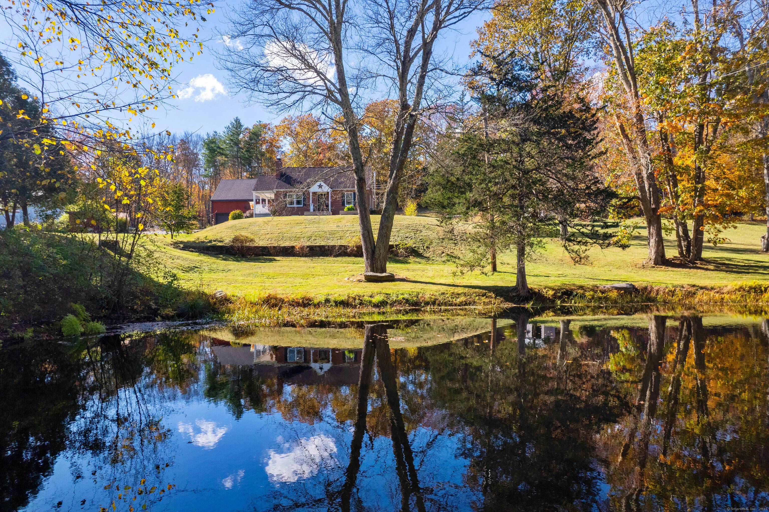 Charming New England brick Cape set on a little over 17 private acres overlooking a picturesque pond and rolling hills.