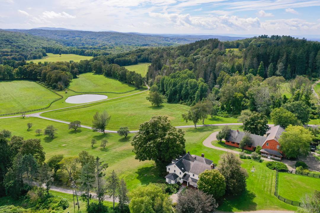 Perched above the rolling hills of Millbrook Hunt Country with sweeping Catskill Mountain views, this idyllic retreat and exceptional equestrian estate spans 185 ultra private acres.