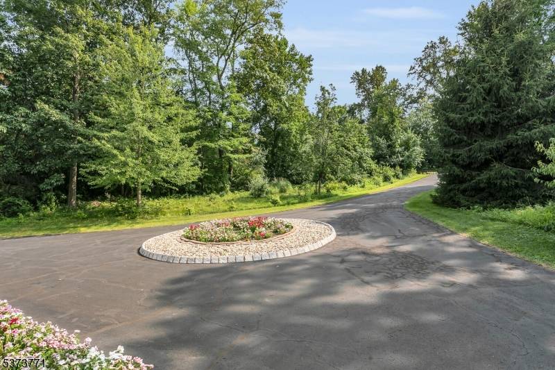 Nestled on nearly 5 acres of private, park like grounds in Basking Ridge, this stunning colonial offers over 5, 000 sq.
