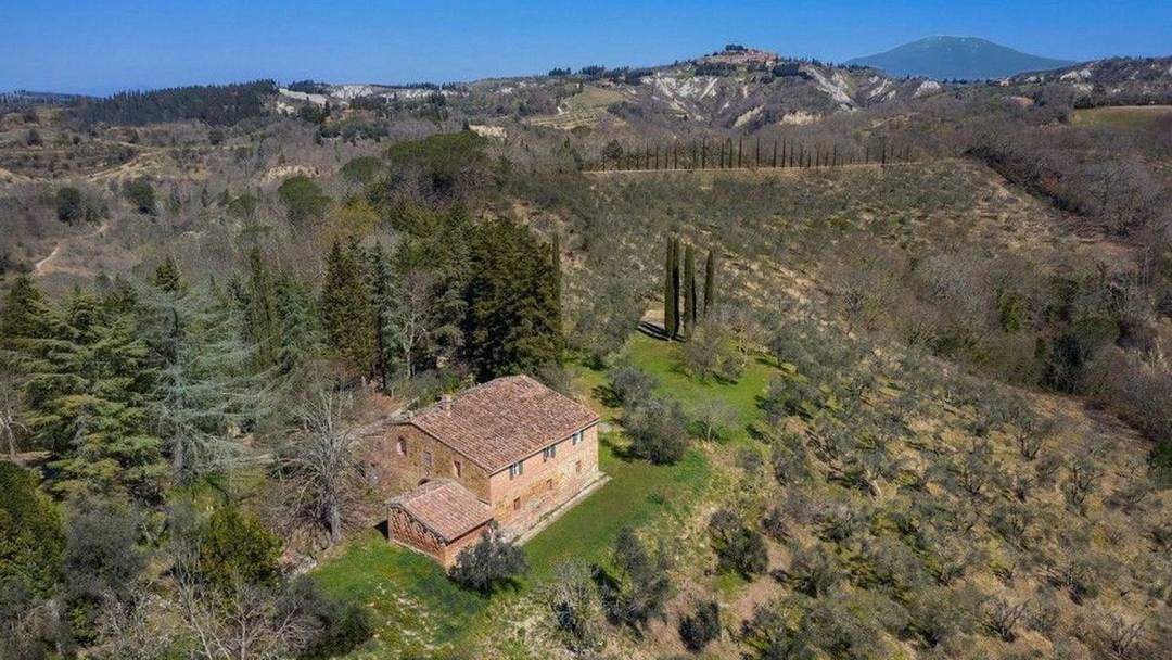 15th-century country house with annexes, 52 hectares of land and panoramic views of the Crete Senesi for sale in Asciano, Tuscany.