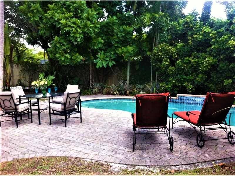 Private tropical back yard has a pool with cascade.