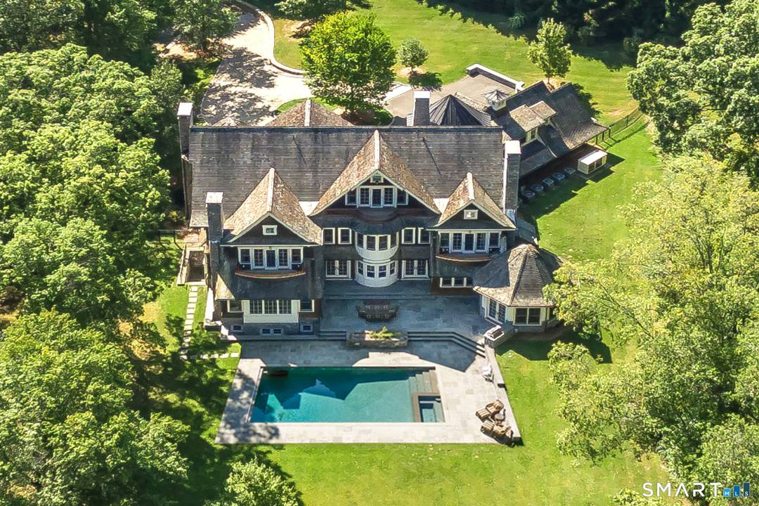 Handsomely set on two private, resort like acres, this timeless Nantucket style residence offers the feel of a secluded family compound.