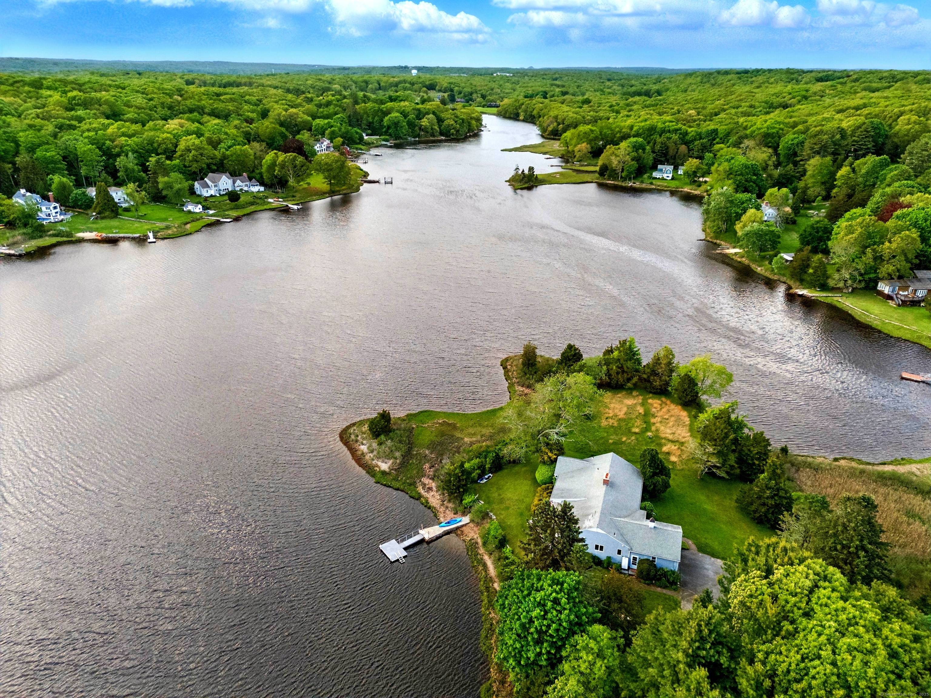 Experience peaceful privacy on over two acres of stunning water frontage on a private road, moments away from the charming downtown Mystic Stonington.