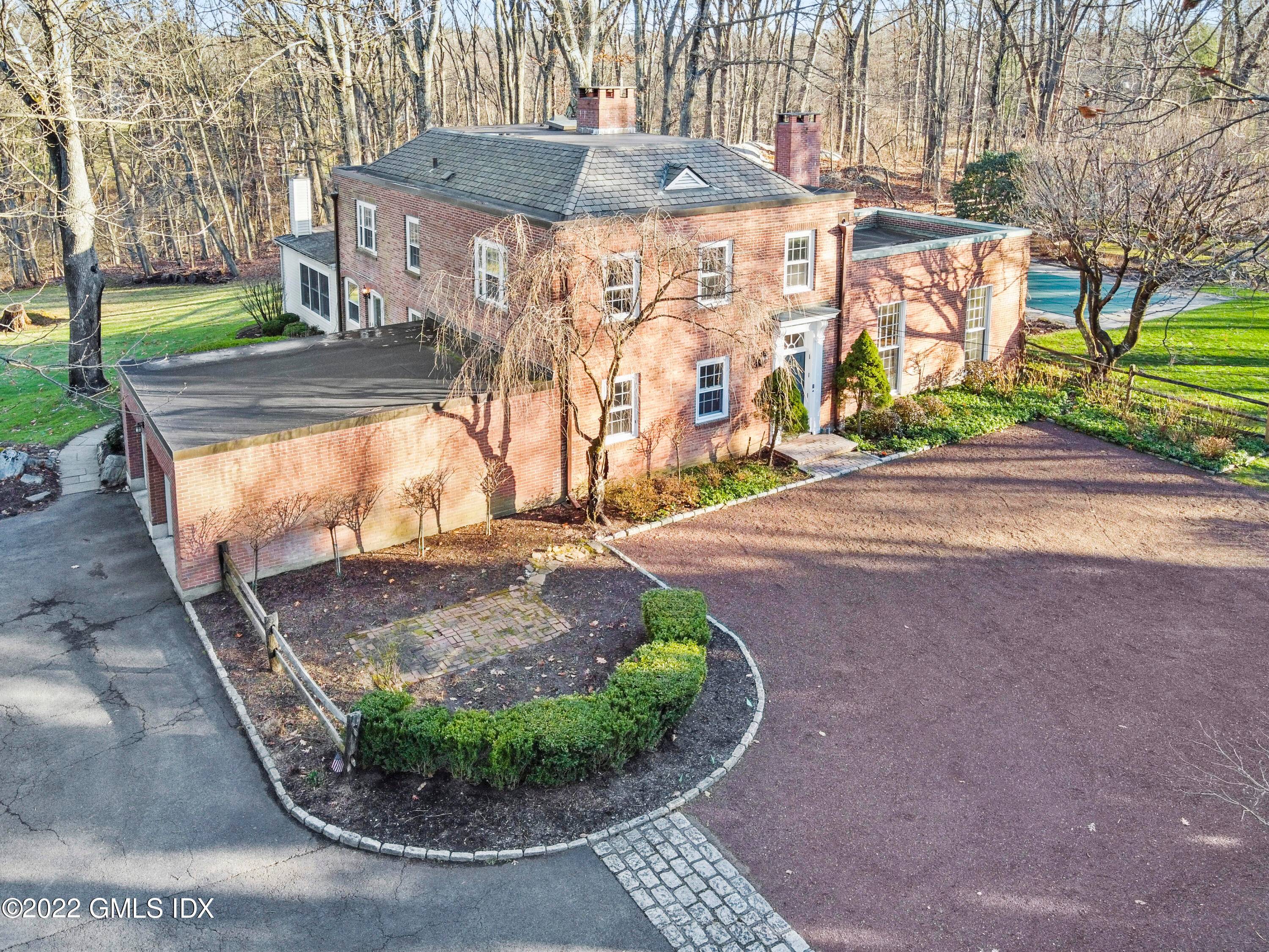 Through a stone wall, up a private drive lined with beautiful mature trees, sits this charming, updated 1940's brick Georgian Colonial.