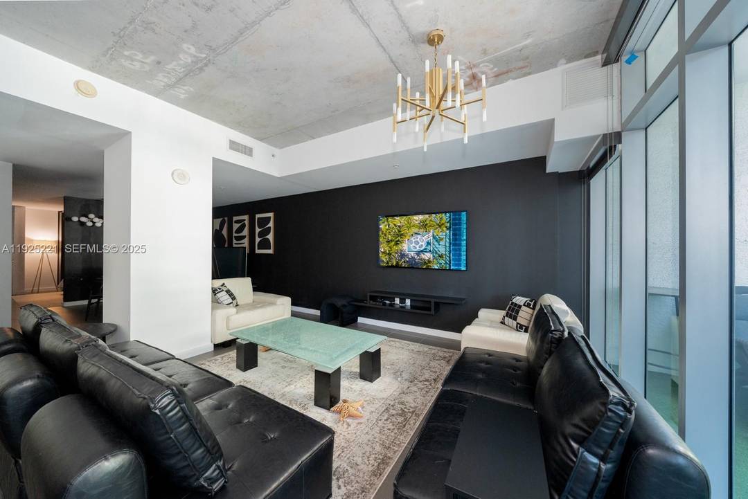 Furnished Studio Den at 4 Midtown featuring 9 ft exposed concrete ceilings, modern finishes, and floor to ceiling windows with abundant natural light.