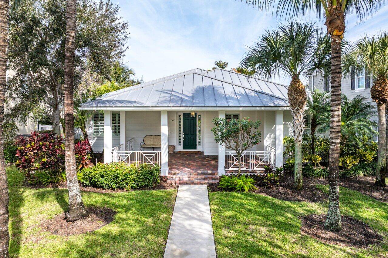 Stunning Key West Style Home welcomes you with an expansive front porch lush Tropical Landscape.