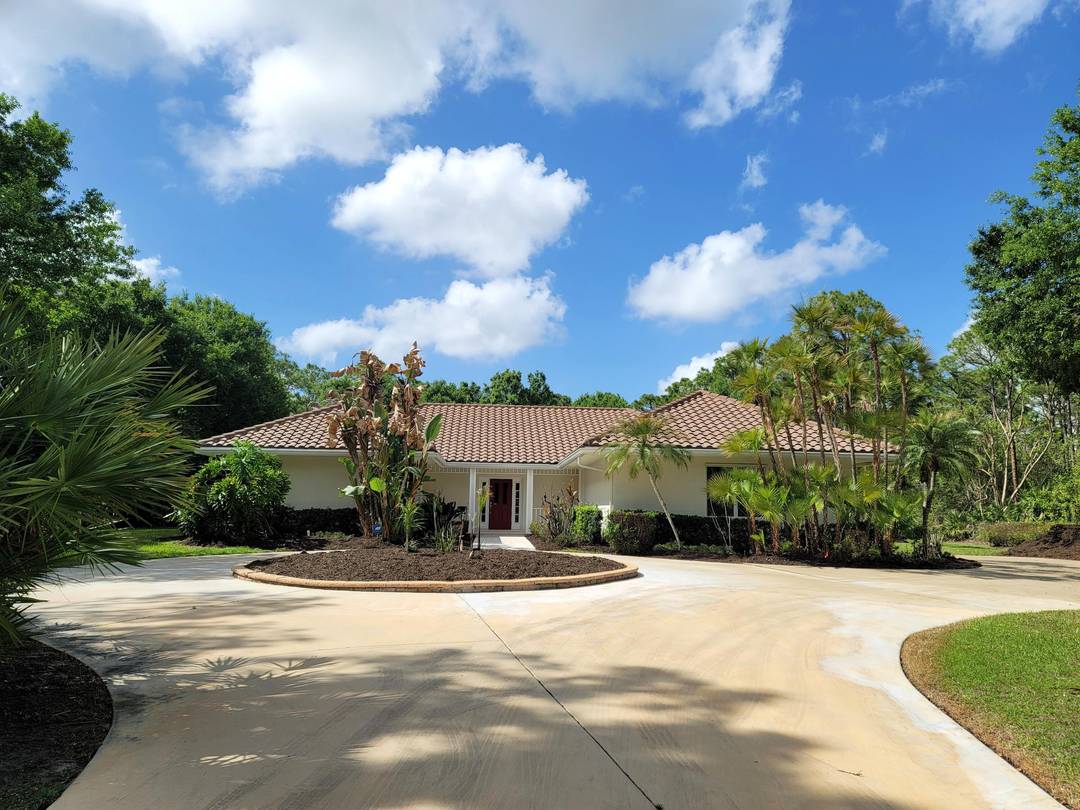 Long driveway with circular turn around leads to this beautiful PGA Village home located on 1.