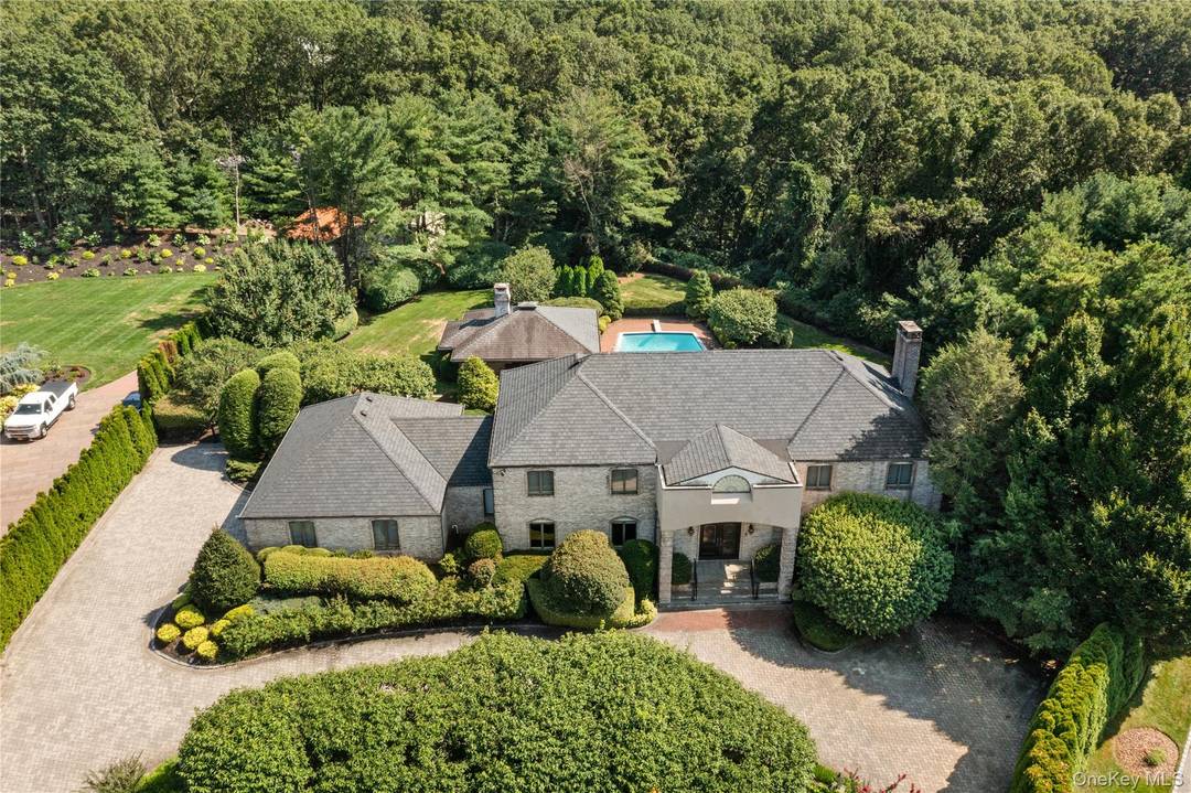 Welcome to 294 Half Hollow Hill Road, a stunning brick colonial perfectly situated on a serene 2.