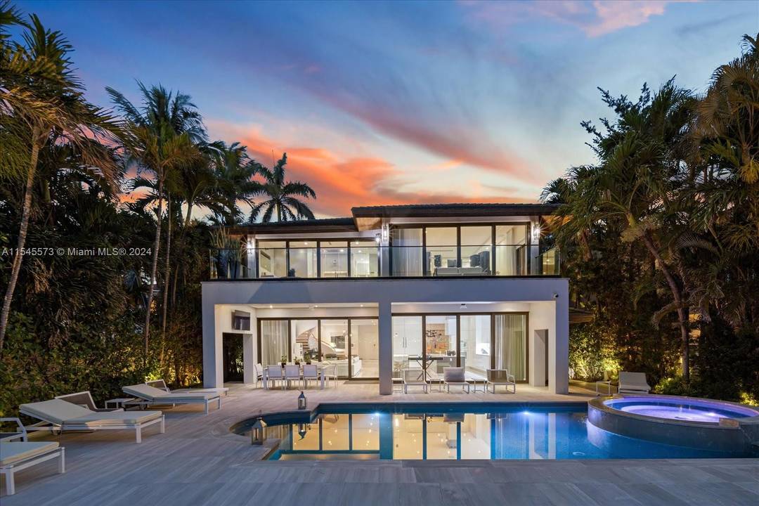 Lush tropical landscaping envelops this exquisite contemporary waterfront residence with mesmerizing vistas of Miami Beach from its expansive floor to ceiling telescopic sliding glass doors.