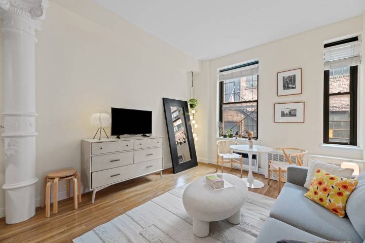This studio loft features a long gallery hallway leading to a beautifully renovated kitchen with stainless steel appliances, quartz counters, white cabinets, large gray tile flooring and white subway tile ...