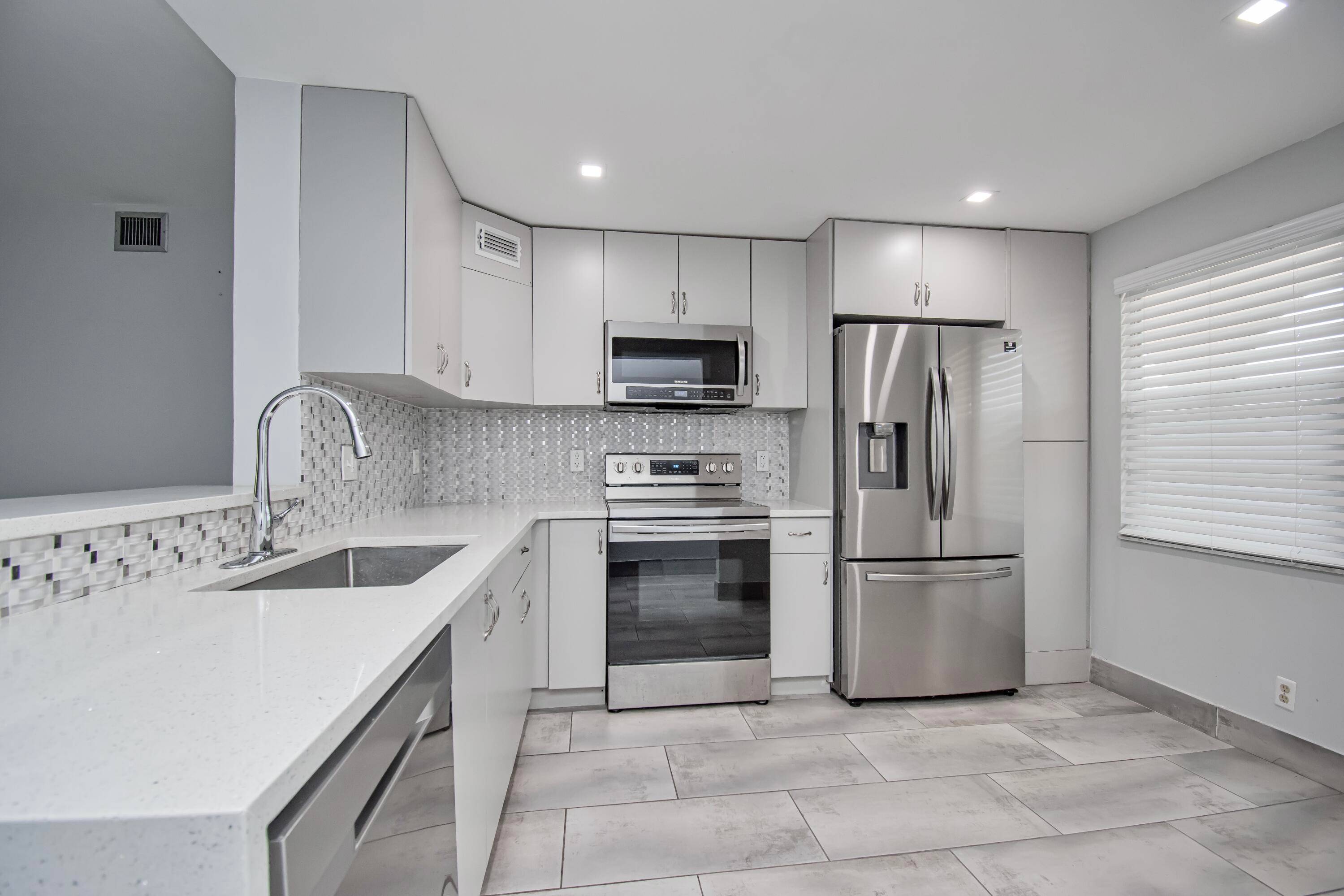 Fully renovated open concept kitchen with s s appliances, quartz counters, tiled thoroughout, modern updated baths, and neutral paint.