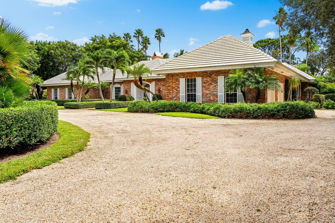 Elegant brick ranch style estate sits on a meticulously landscaped 1.