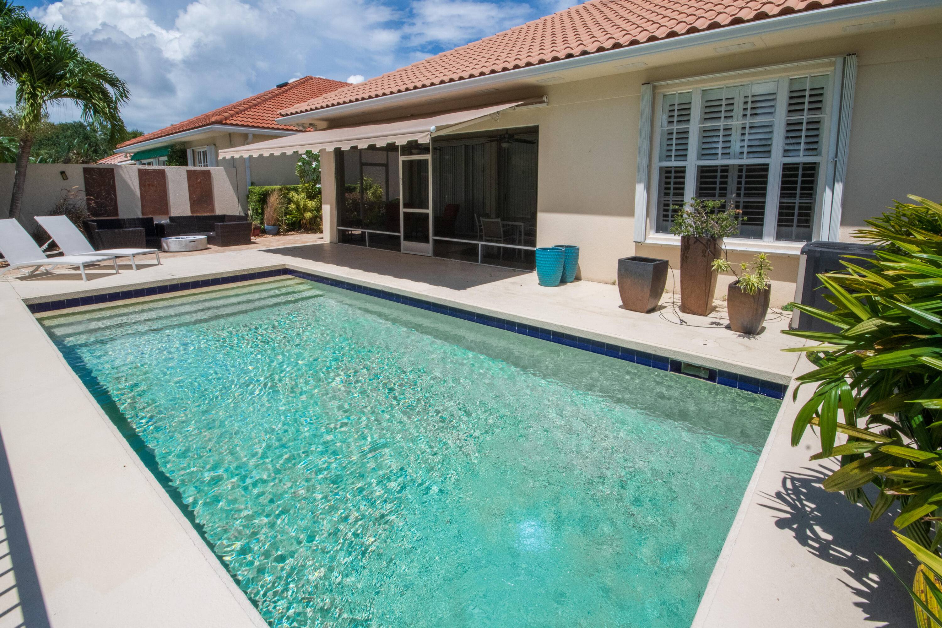 Charming Private Lakefront Pool Home with extended Patio deck area, Remote Sun Shade Awning, lovely covered screened Patio area Lush Landscaping.